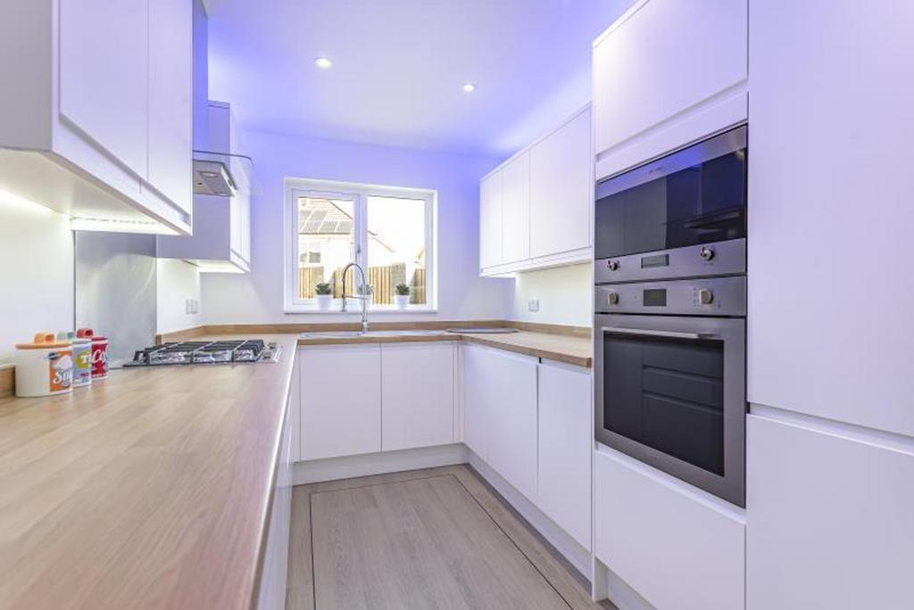 A modern kitchen with sleek white cabinetry, am...
