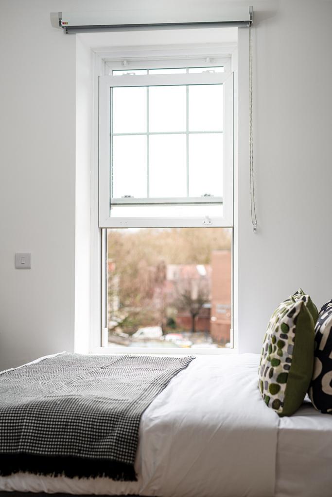 A cozy double bedroom featuring a well-lit wind...