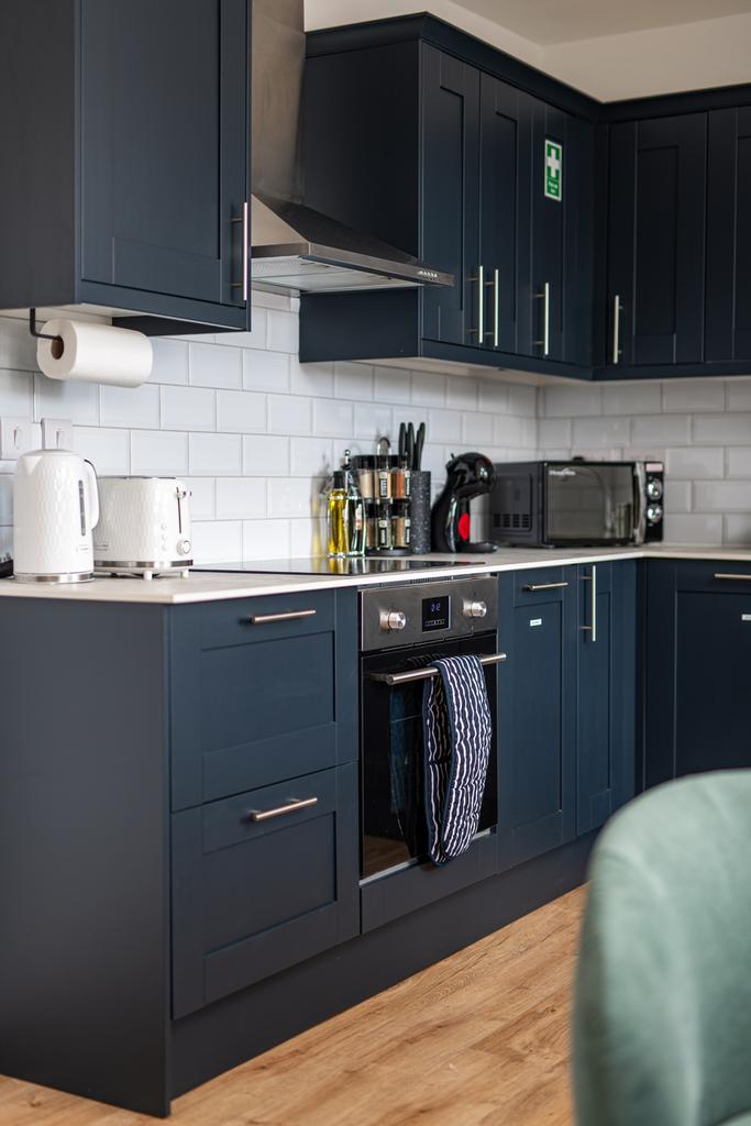 Modern kitchen featuring sleek navy cabinets, a...
