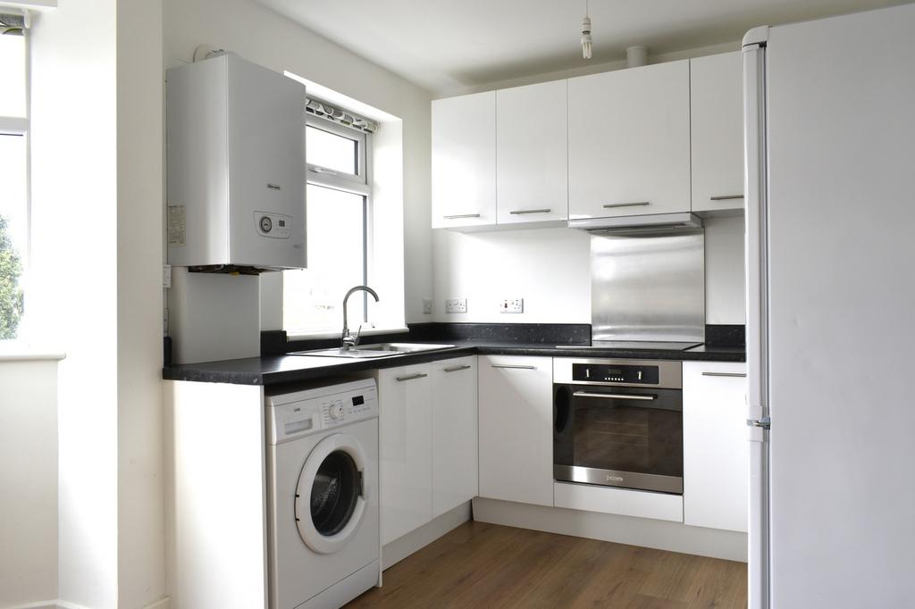 This modern kitchen features sleek white cabine...