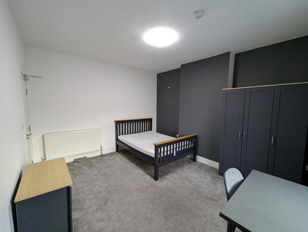This spacious double bedroom features a modern ...