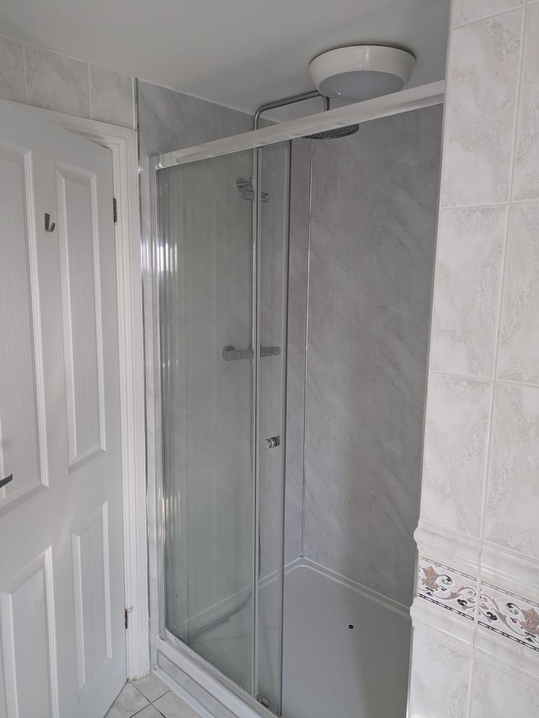 A modern bathroom featuring a sleek glass showe...
