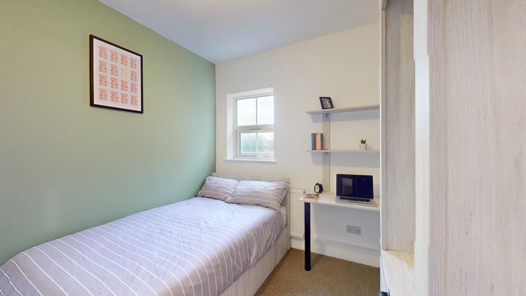 A bright and tidy single bedroom with a comfort...