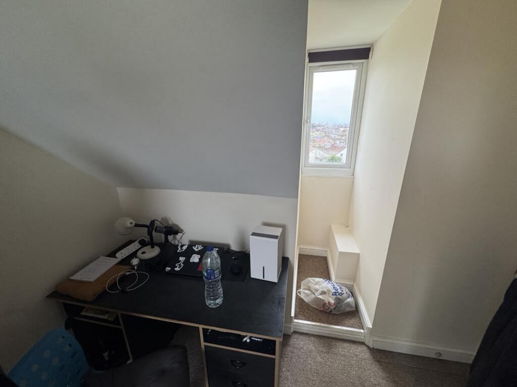 A cozy single bedroom featuring a study desk an...