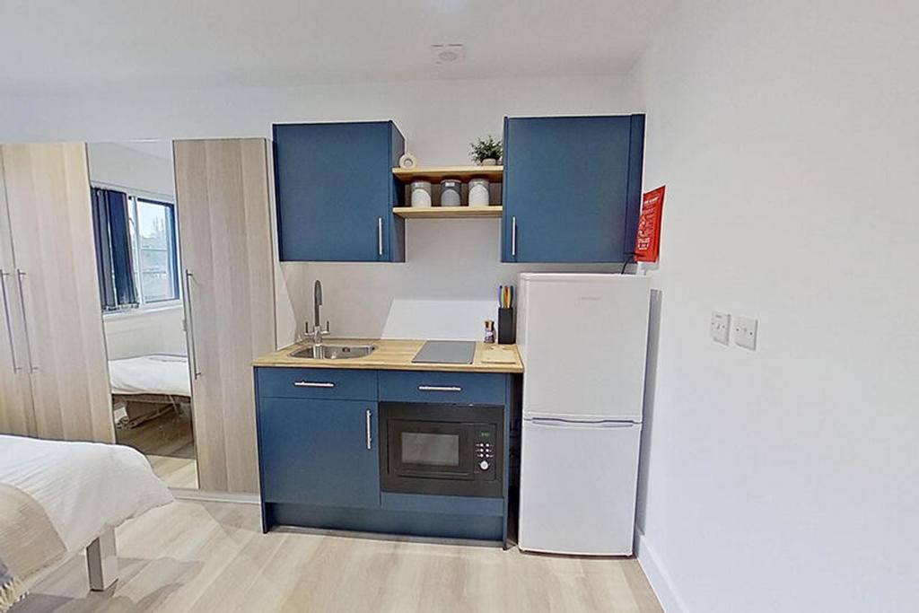 This modern kitchenette features sleek blue cab...