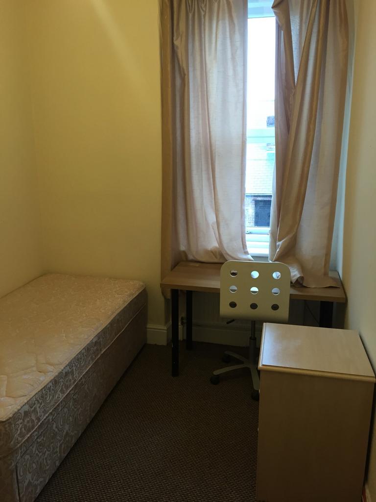 Cozy and well-lit single bedroom featuring a co...