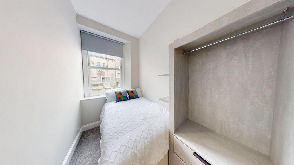 A bright and tidy single bedroom featuring mode...