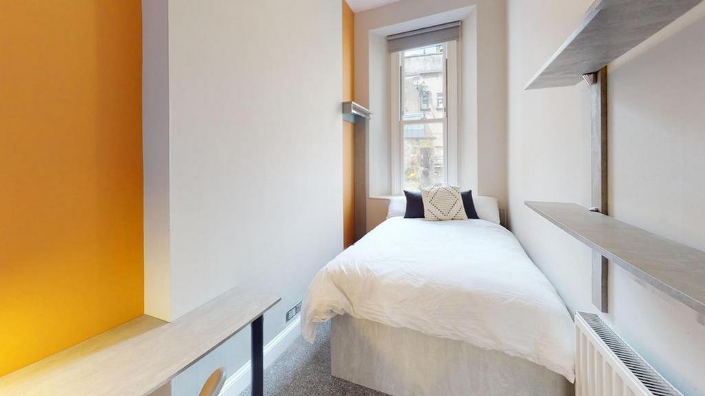 A bright and tidy single bedroom featuring mode...