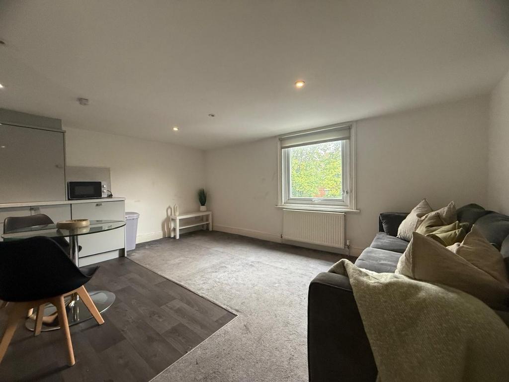 Bright, modern lounge with seating and kitchene...