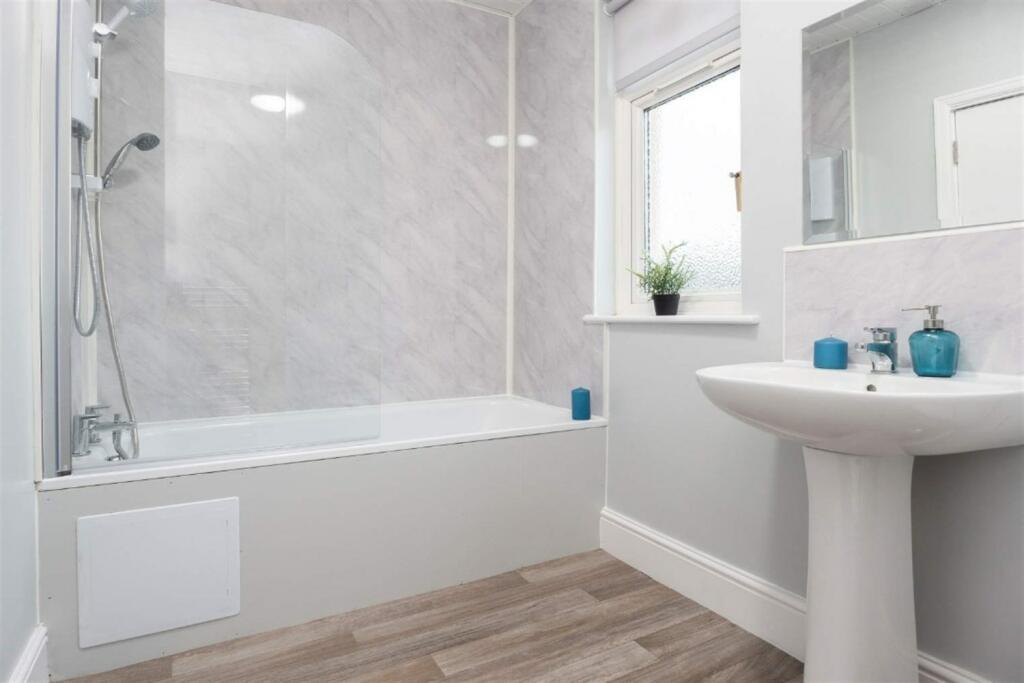 A bright and clean bathroom suite featuring a m...