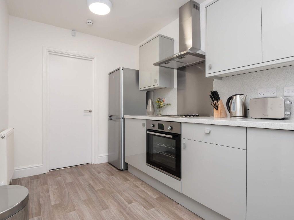 Modern kitchen with sleek white cabinetry, buil...