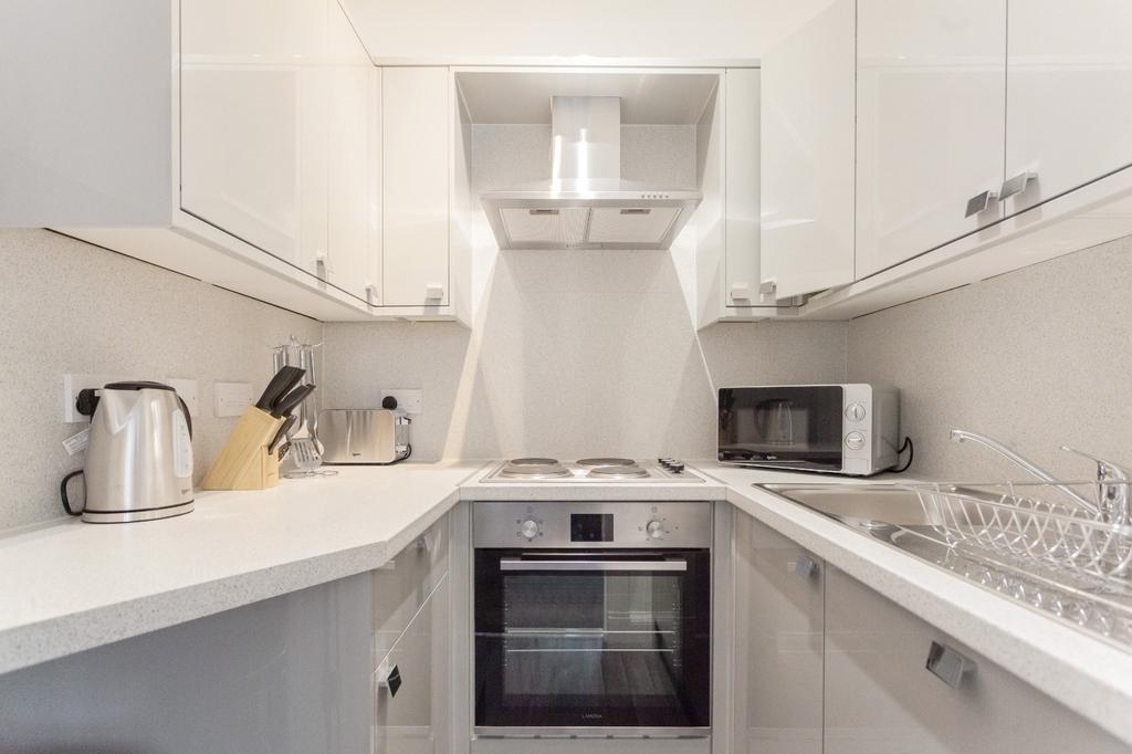 A modern compact kitchen featuring white cabine...