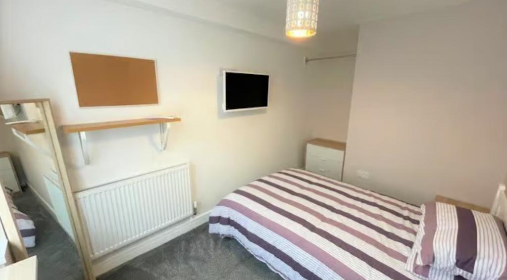A cozy single bedroom featuring a neatly made b...