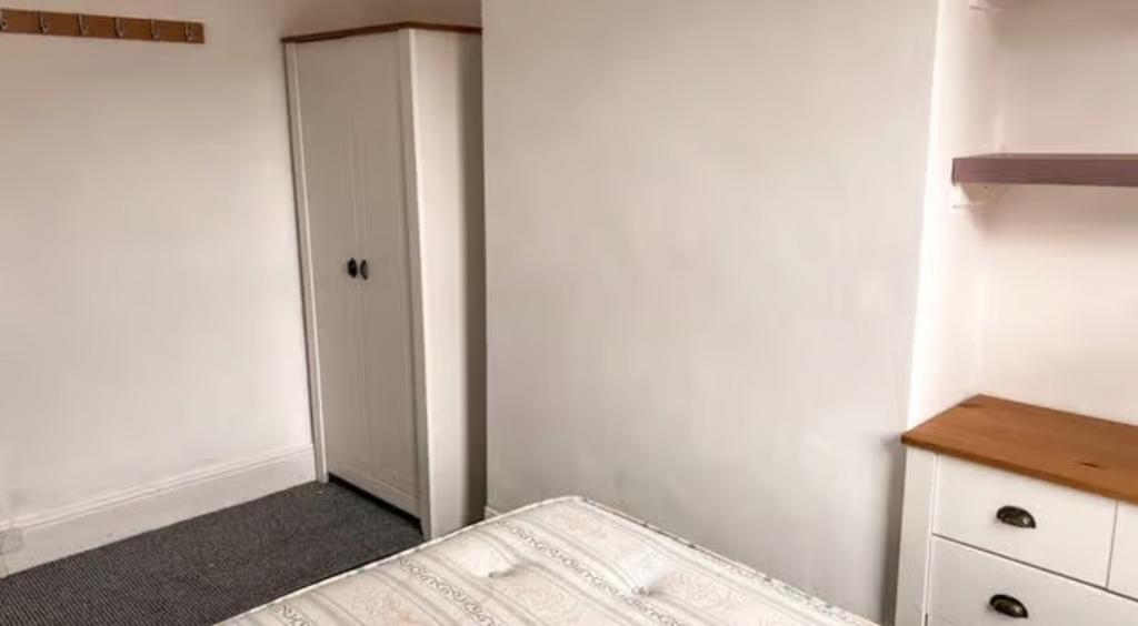A cozy single bedroom featuring a wardrobe, che...