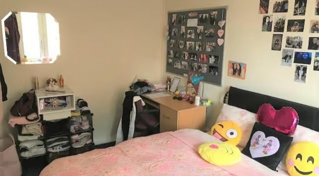 A cozy single bedroom featuring a neat study de...