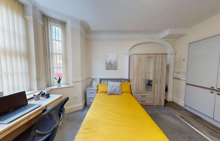 Bright single bedroom featuring a cozy bed with...