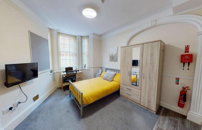 A cozy single bedroom featuring a bright yellow...
