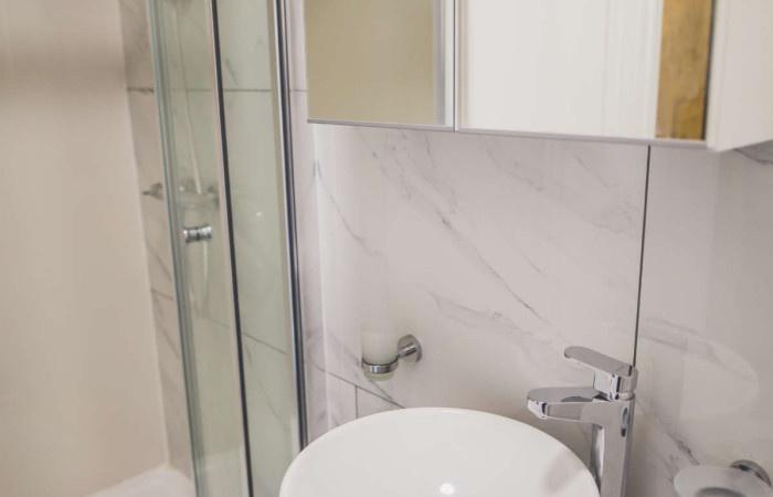A modern bathroom featuring a sleek white basin...
