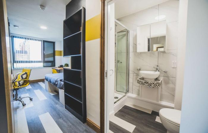 A modern and tidy single bedroom with a desk an...