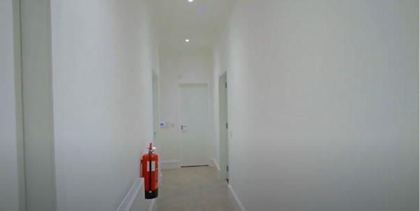 A clean and well-lit hallway with white walls a...