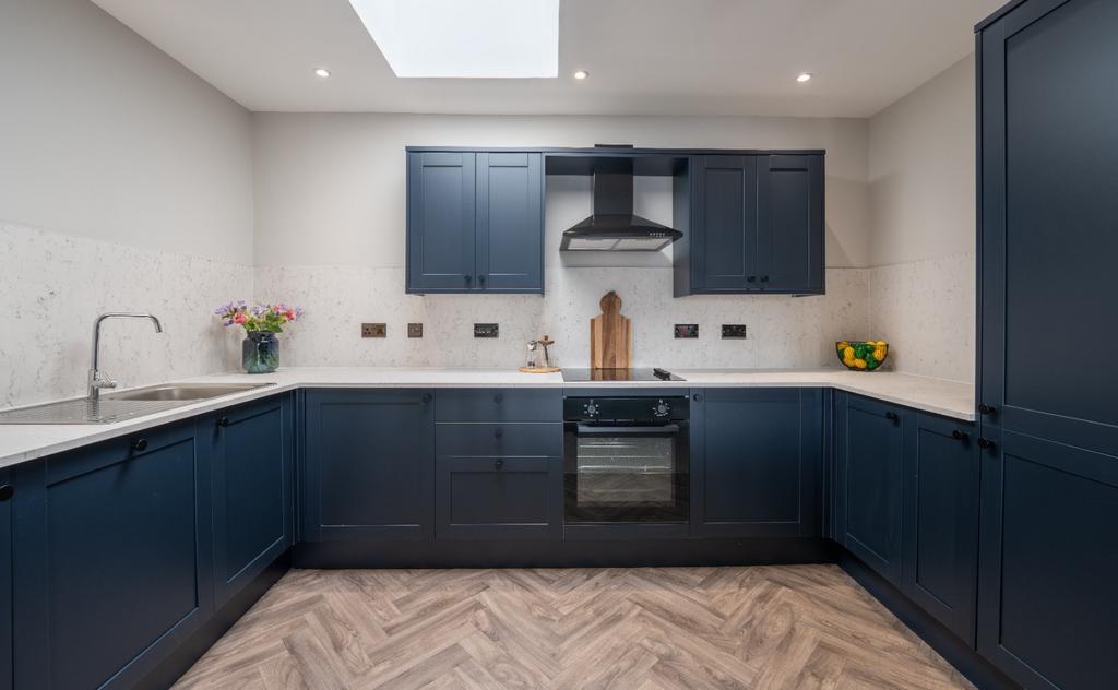 This modern kitchen features sleek navy cabinet...