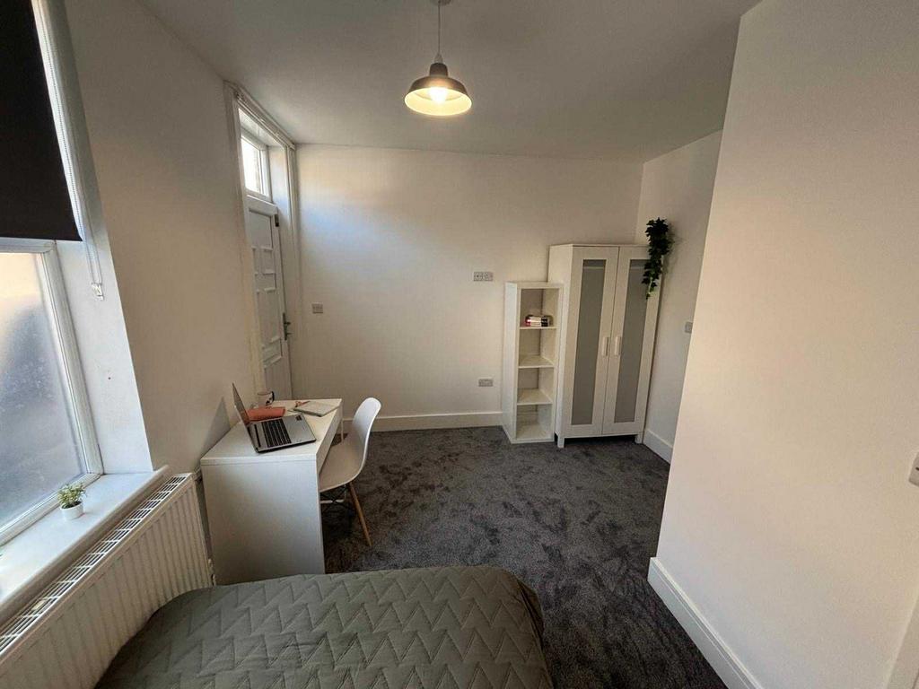 A bright and clean bedroom featuring a small de...