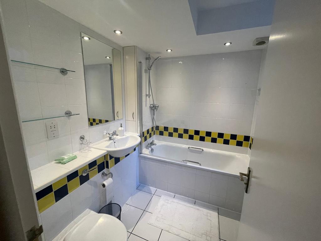 A spacious and bright bathroom featuring a bath...