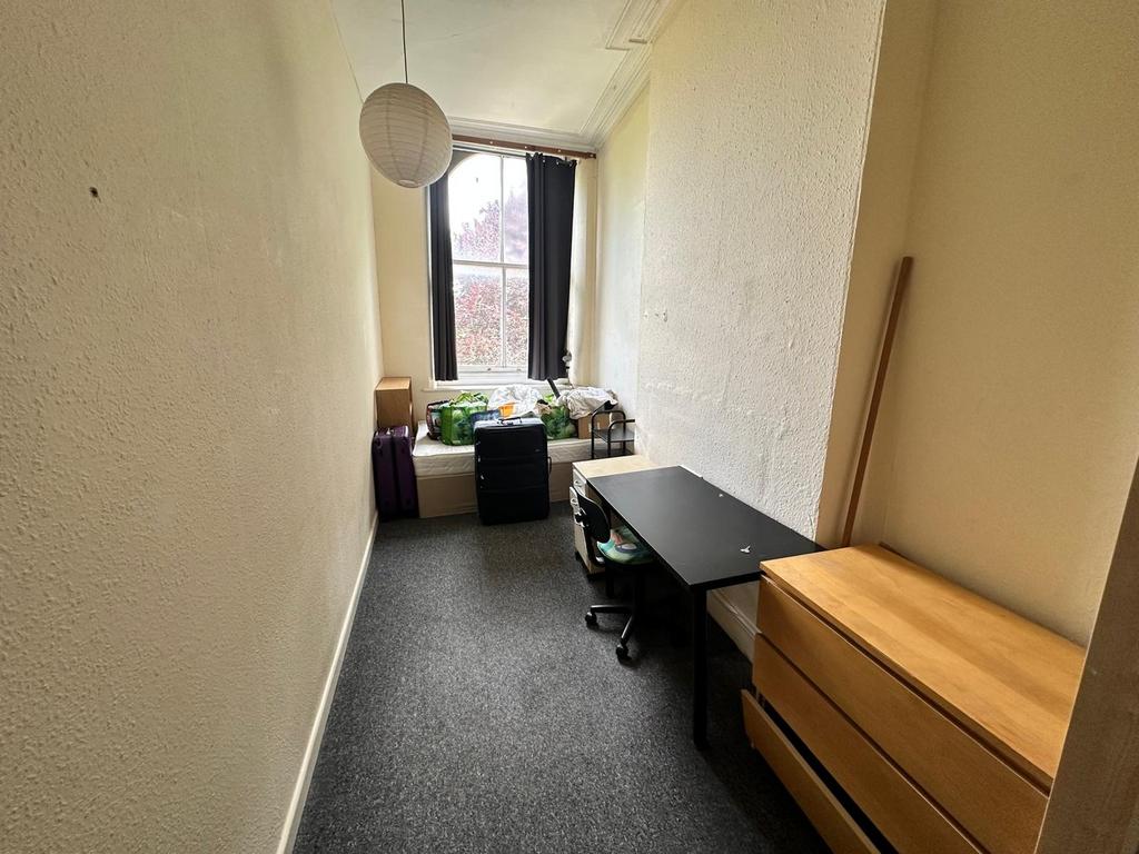 A cozy single bedroom with a desk and storage, ...