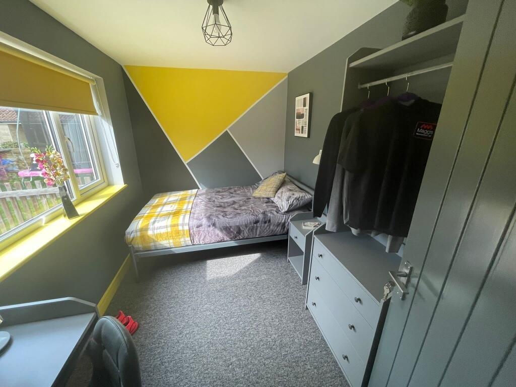 A cozy single bedroom featuring a stylish geome...