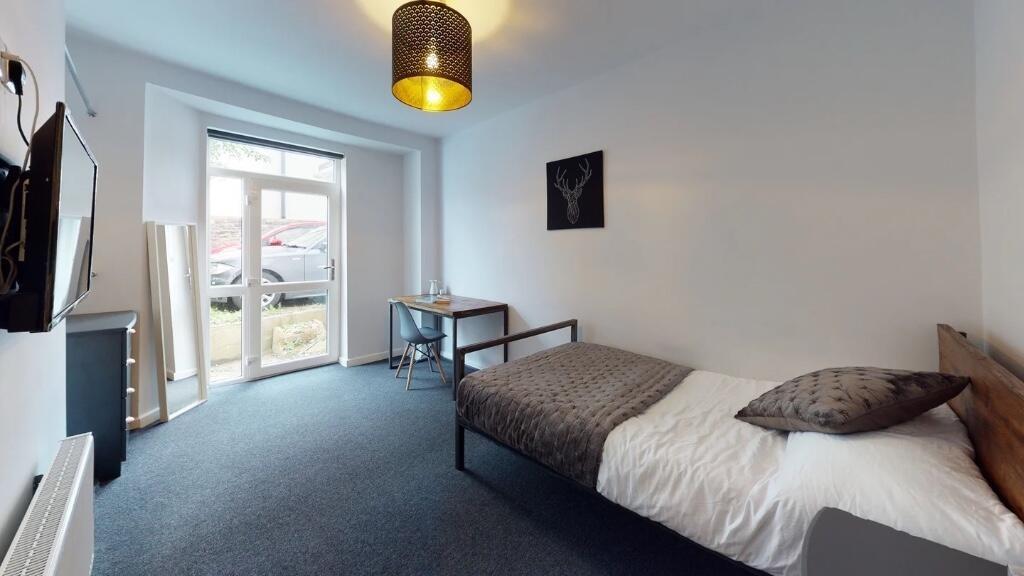 A bright, tidy single bedroom featuring a comfo...