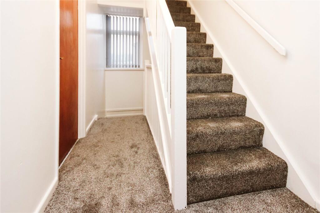 A clean and neat hallway featuring soft carpete...