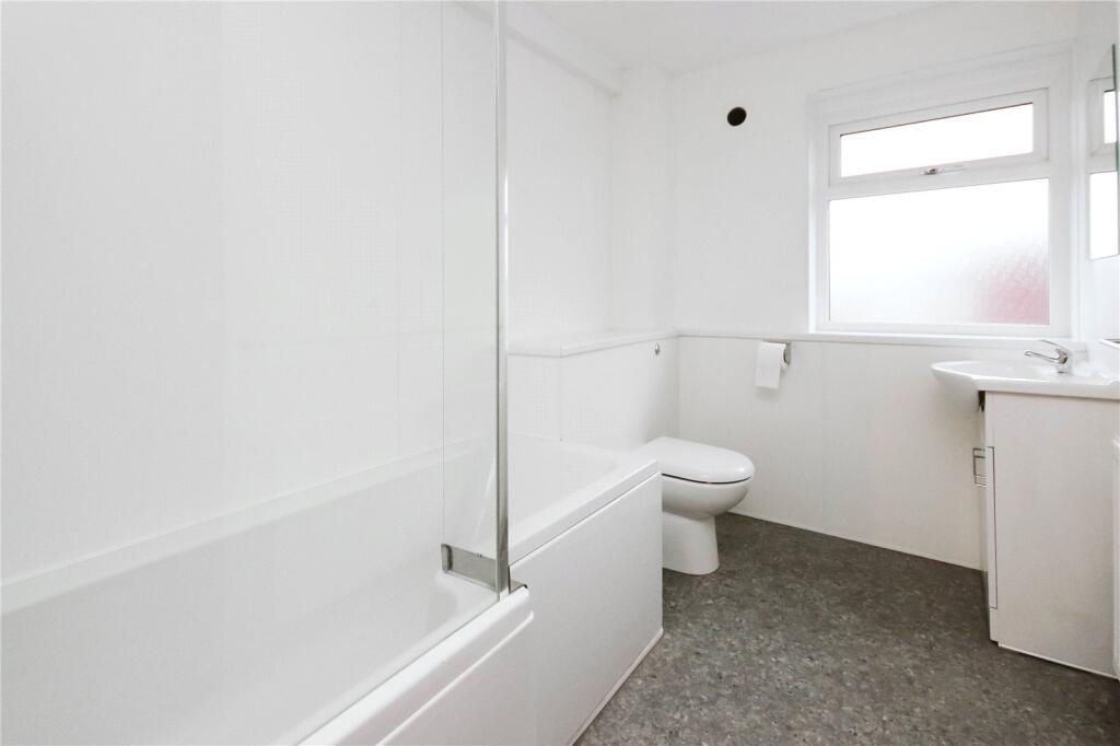 A clean and bright bathroom featuring a bathtub...