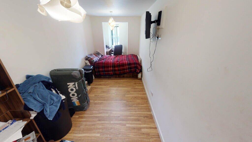 A neat and narrow single bedroom with a wooden ...