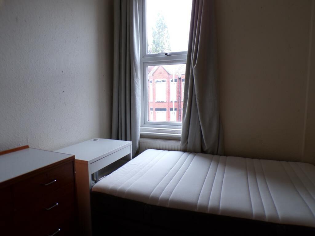 A cozy single bedroom featuring a large window ...
