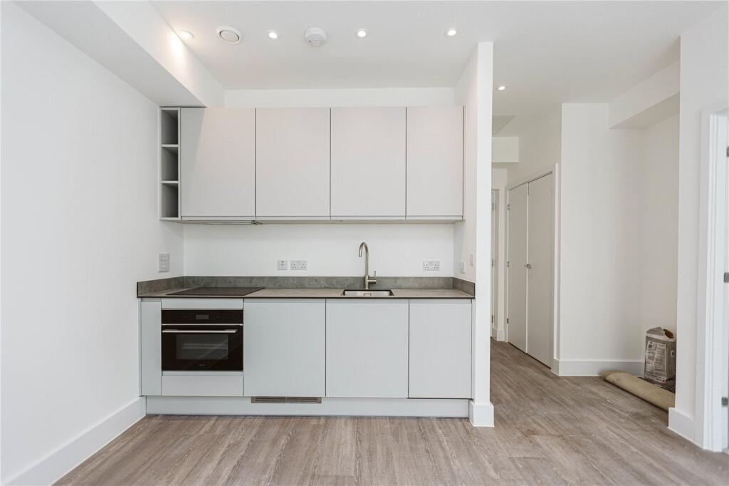 A modern, compact kitchen featuring white cabin...