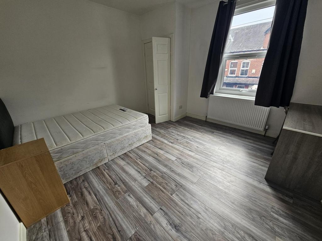 A modest single bedroom featuring a simple bed ...