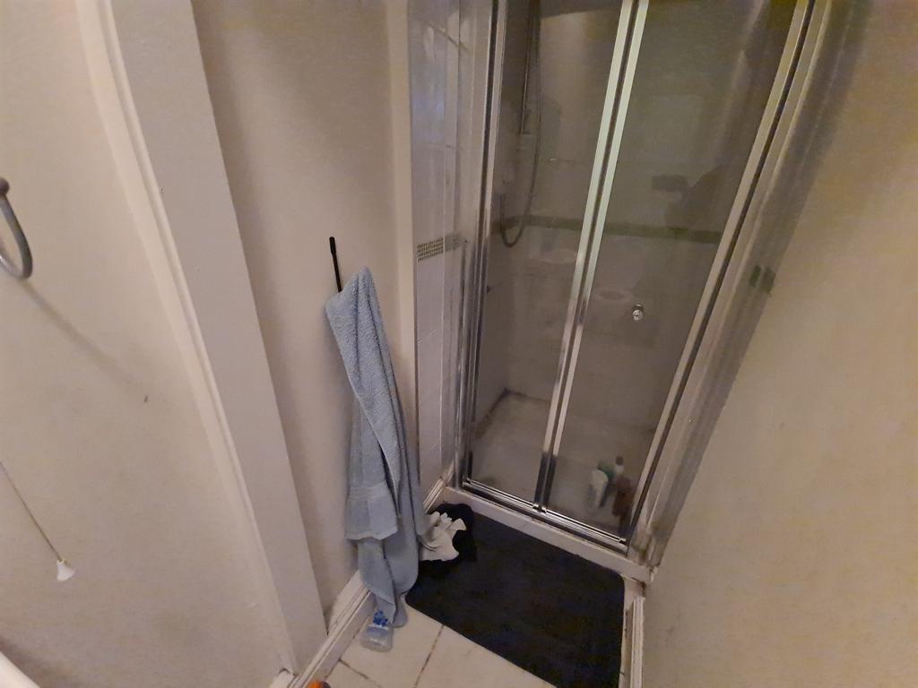 A compact bathroom featuring a shower enclosure...