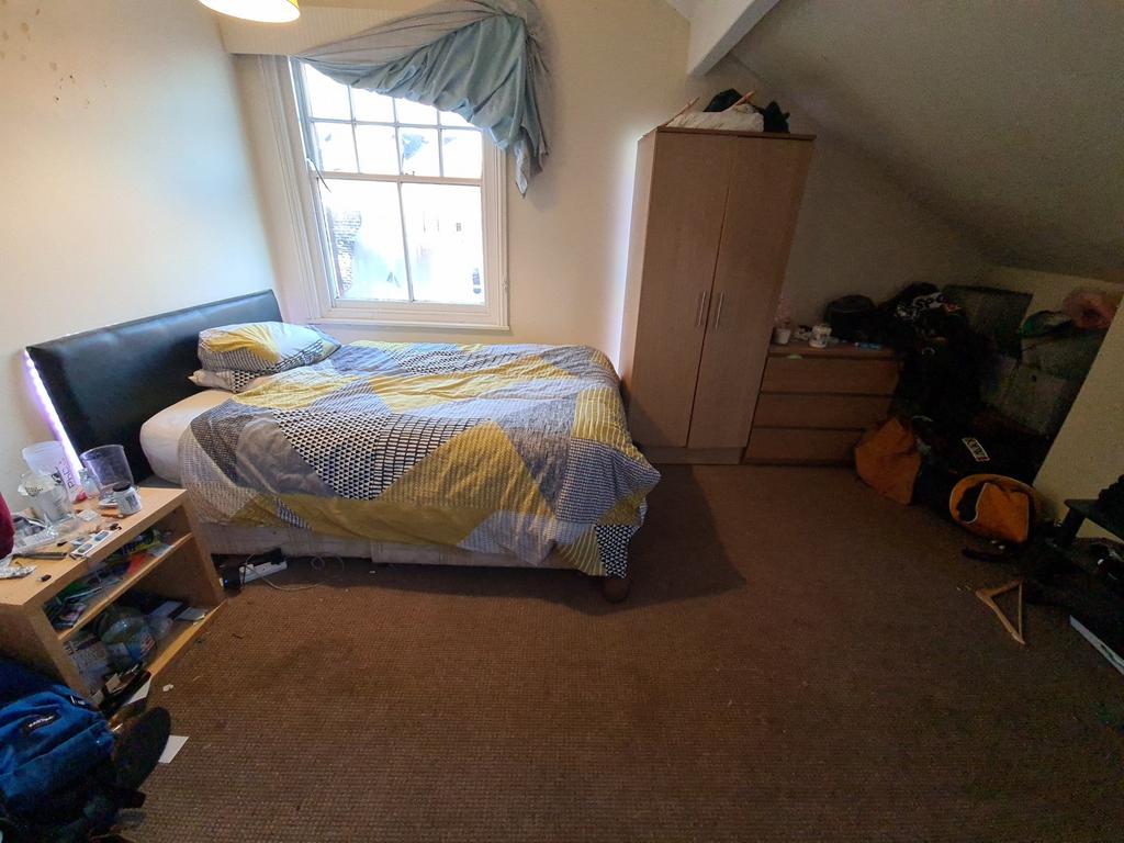 A cozy attic bedroom with a single bed position...