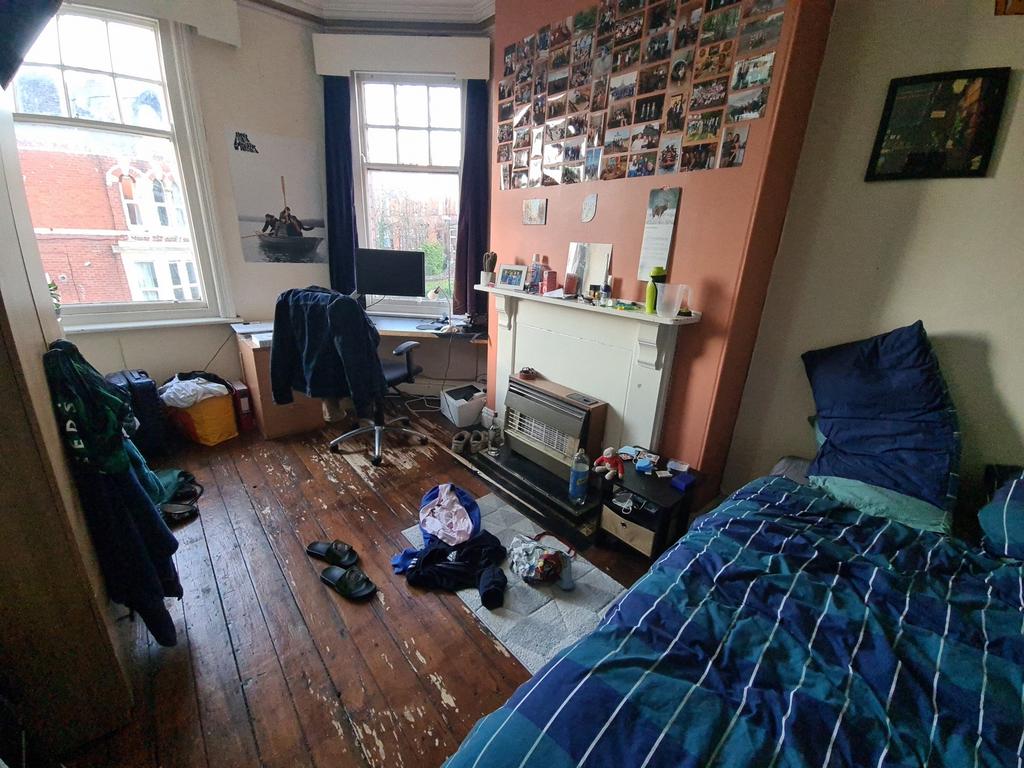 A cozy single bedroom featuring a large window ...