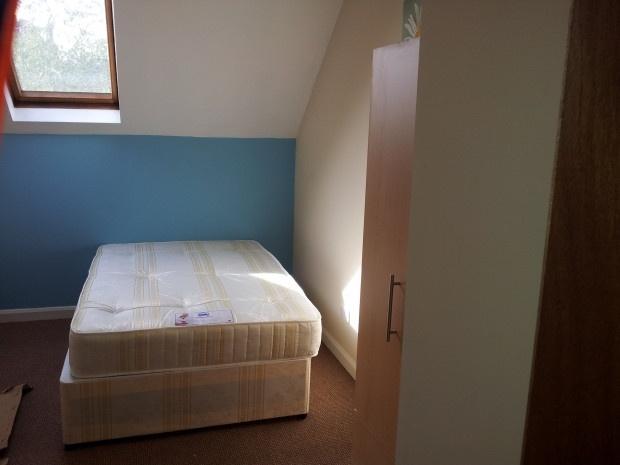 A cozy single bedroom featuring a comfortable b...