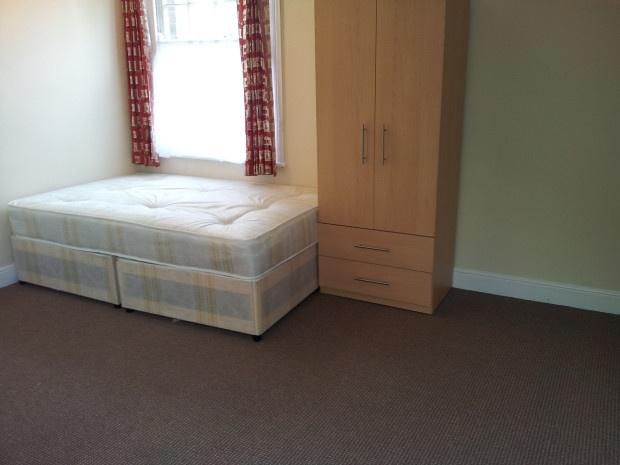 A simple, clean single bedroom featuring a bed ...