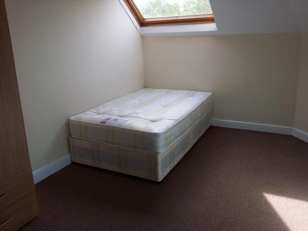 A bright single bedroom featuring a comfortable...