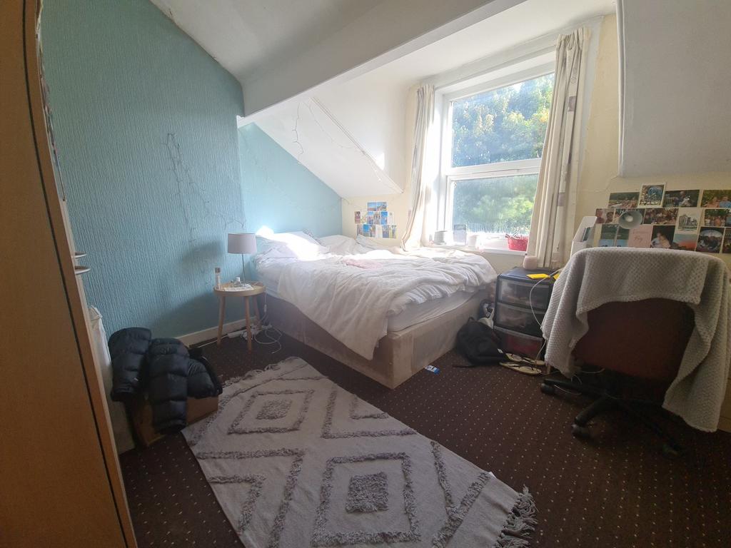 A cozy bedroom featuring a single bed positione...