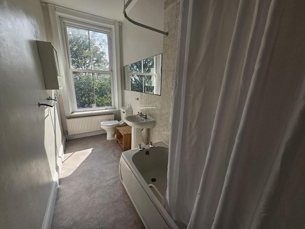 A bright and clean bathroom with a large bathtu...