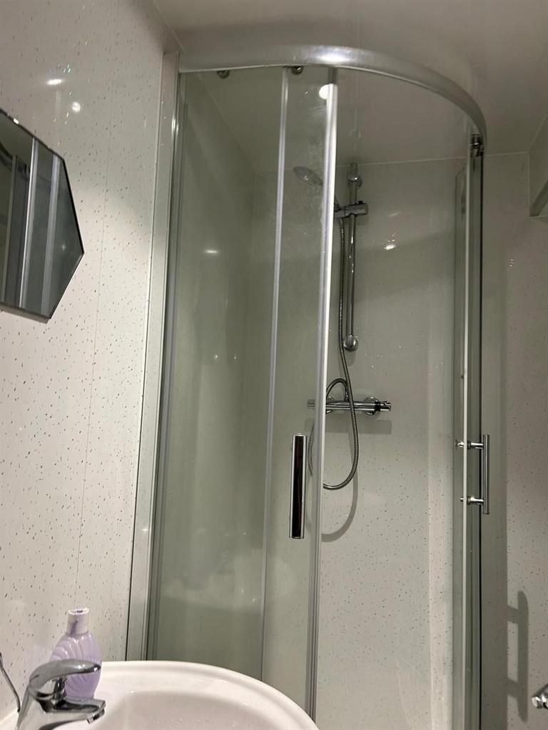 Bright, modern bathroom with a curved glass sho...