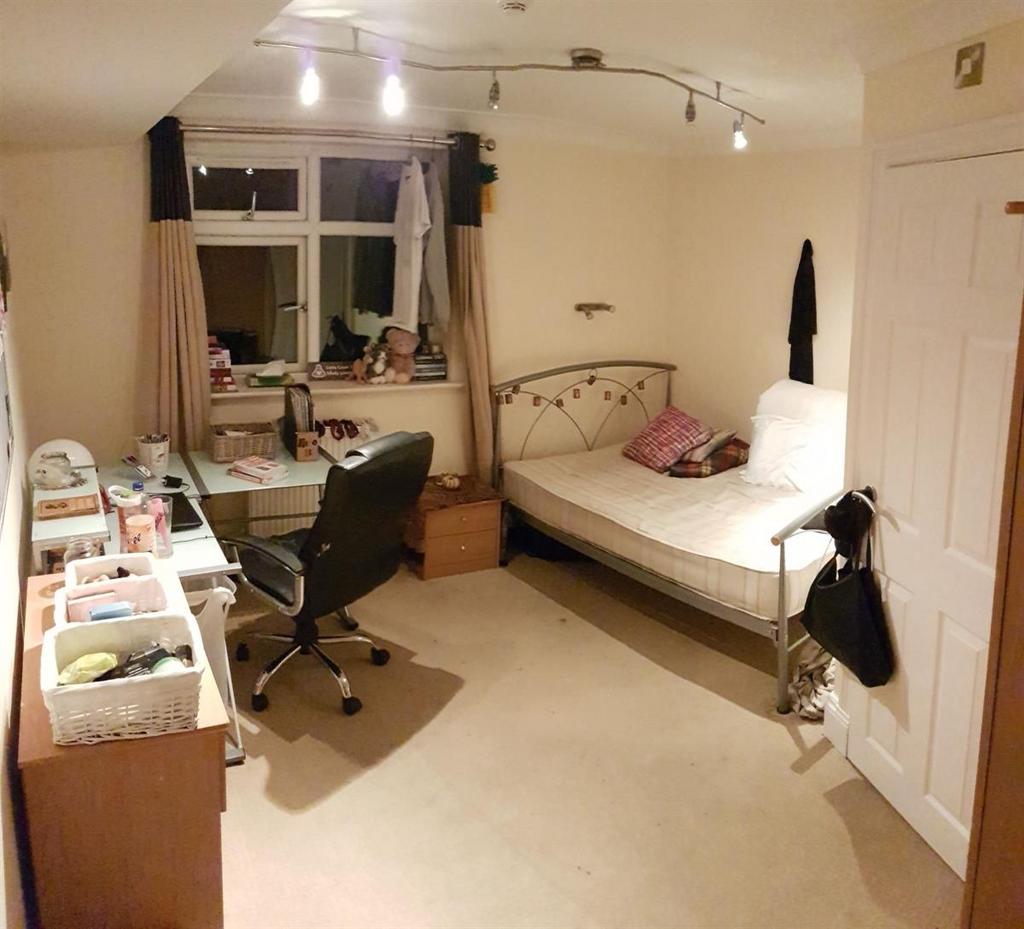 A tidy, well-lit student bedroom featuring a si...