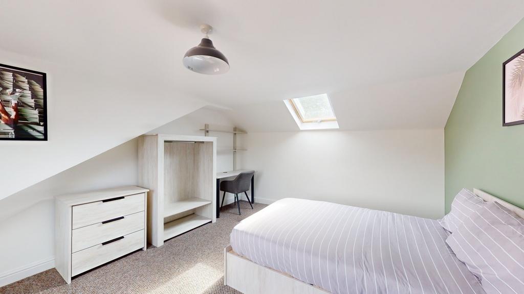 A bright and tidy double bedroom with a cozy at...