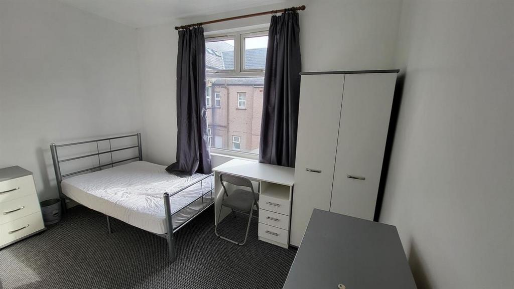 A neat, well-lit single bedroom featuring a met...