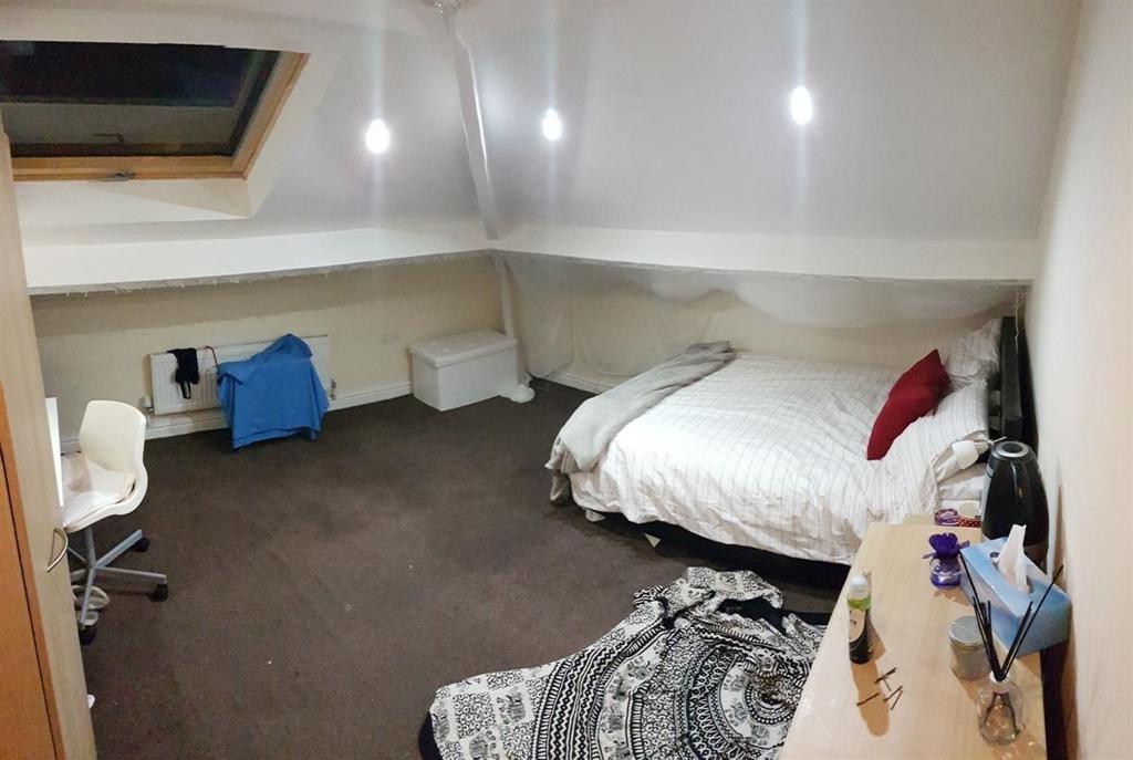 A spacious and cozy attic bedroom featuring a d...