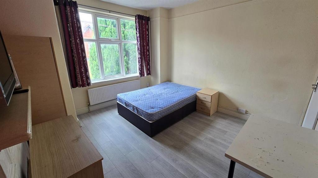 A bright double bedroom featuring a large windo...